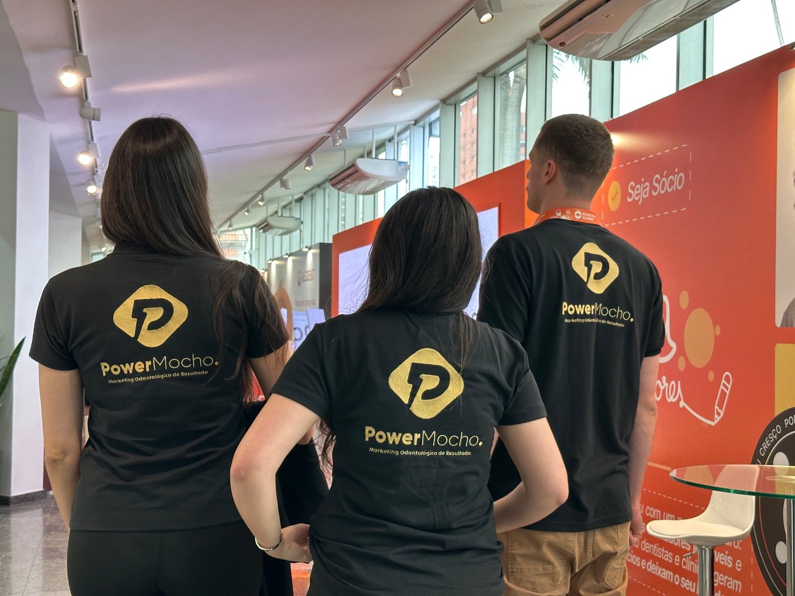 Três membros da Power Mocho vistos de costas durante o Clinicorp Summit